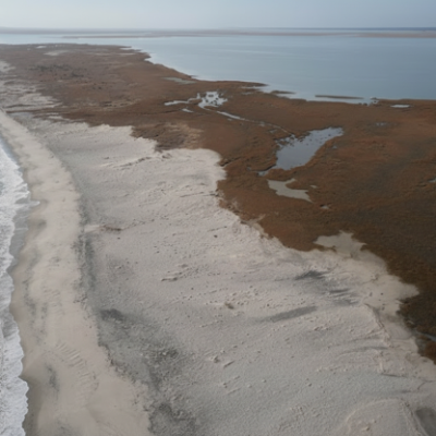 Aerial view of Cedar Island, North Carolina, showing a sandy shoreline between ocean waves and expansive brown coastal marsh with winding tidal channels.